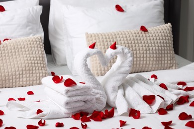 Honeymoon. Swans made with towels and beautiful rose petals on bed