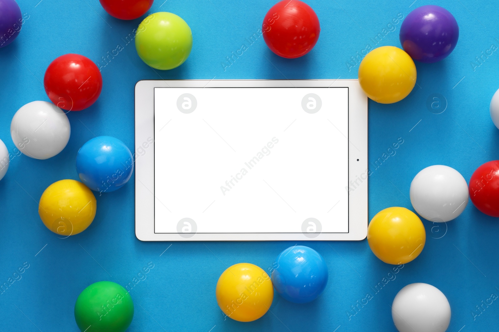 Photo of Modern tablet and balls on light blue background, flat lay. Space for text