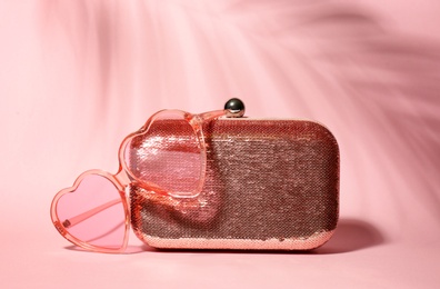 Photo of Stylish heart shaped glasses and purse on color background