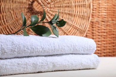 Photo of Stacked terry towels and green branch on white table