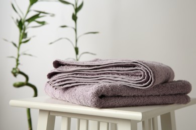 Violet towels on stool against white wall, closeup