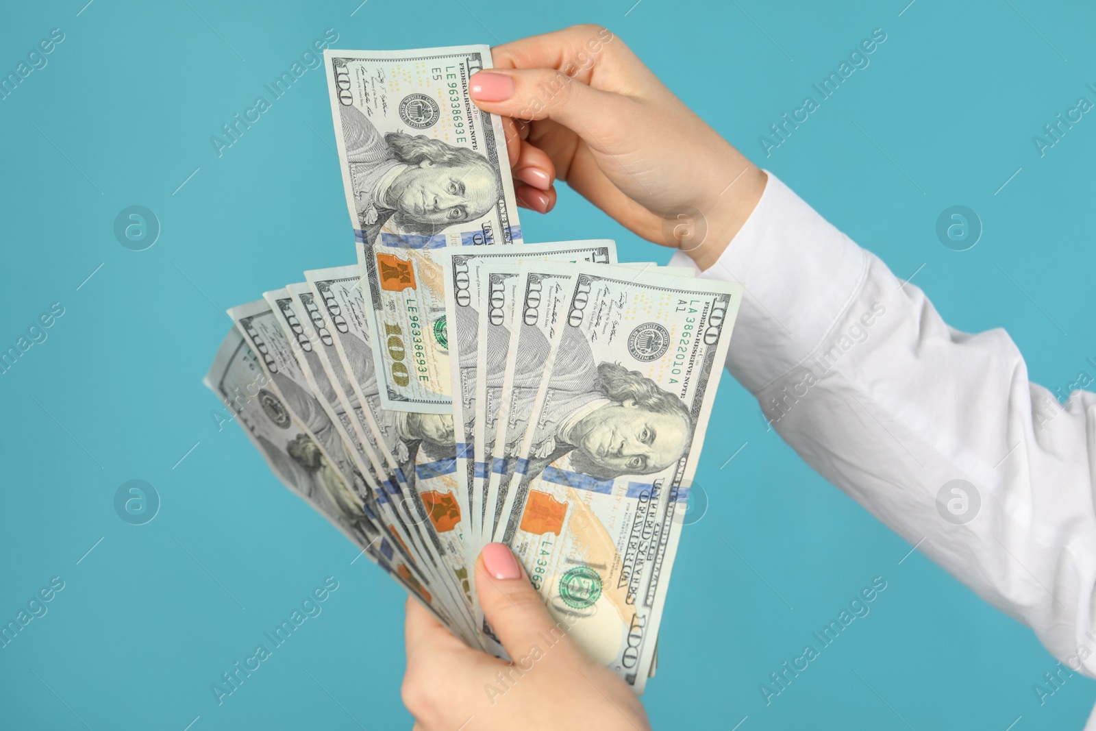 Photo of Woman holding dollar banknotes on turquoise background, closeup. Money exchange concept