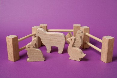 Photo of Wooden animals and fence on purple background. Children's toy