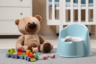 Photo of Light blue baby potty and toys on carpet in room. Toilet training