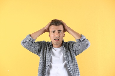 Handsome emotional young man on color background