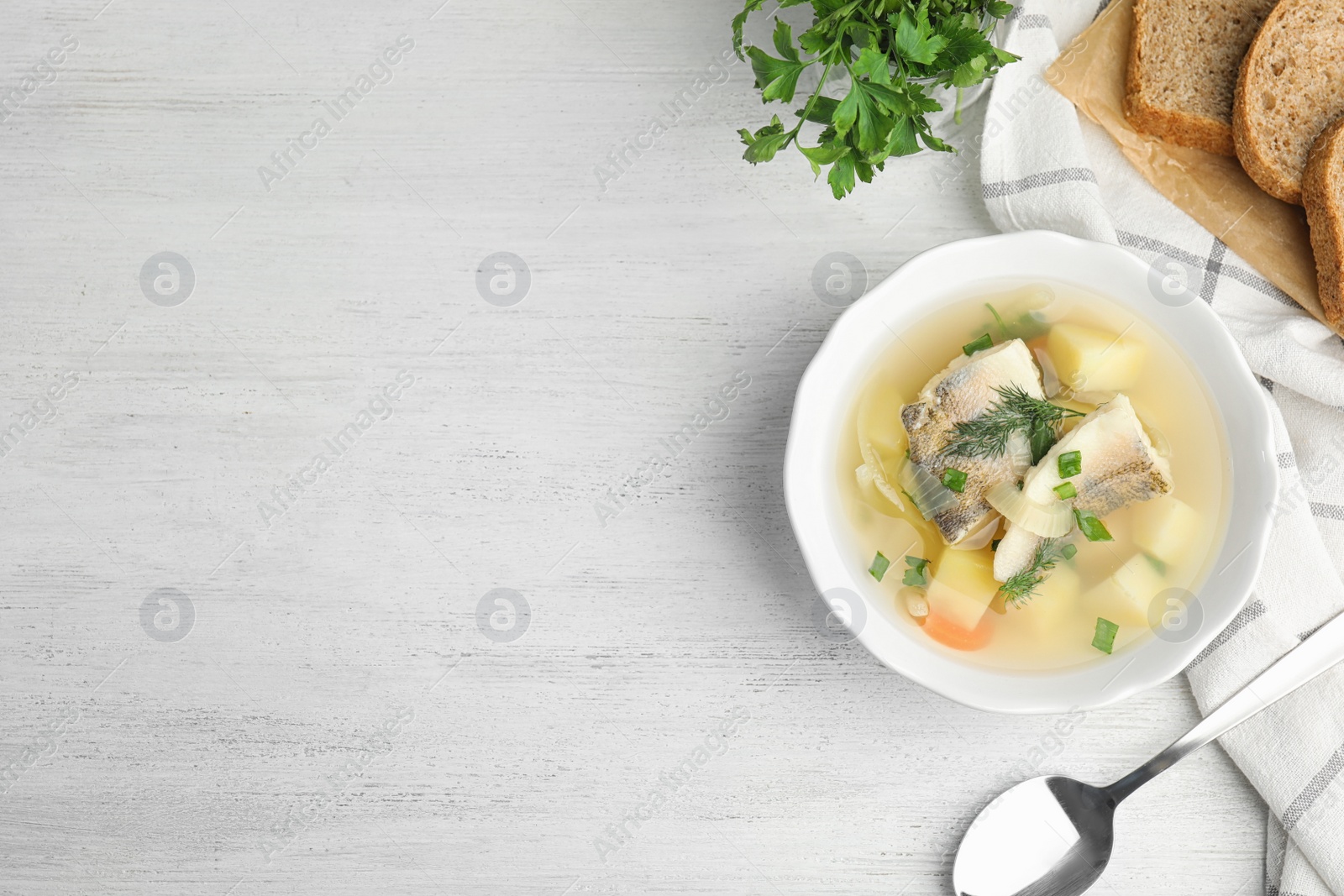 Photo of Delicious fish soup served on white wooden table, flat lay. Space for text