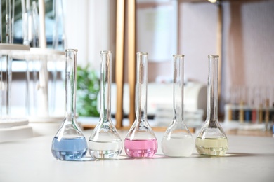 Photo of Glassware with colorful liquids on table indoors. Laboratory analysis