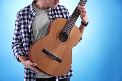 Photo of Young man playing acoustic guitar on color background, closeup