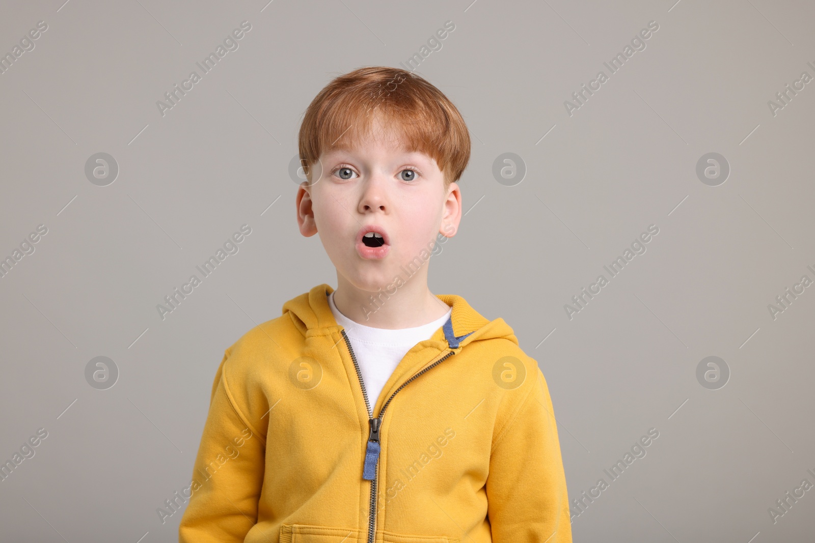 Photo of Portrait of surprised little boy on grey background