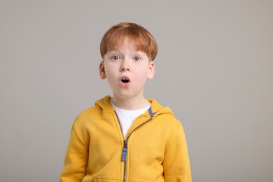 Portrait of surprised little boy on grey background