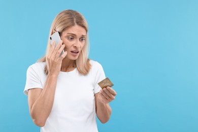 Photo of Stressed woman with credit card talking on smartphone against light blue background, space for text. Be careful - fraud