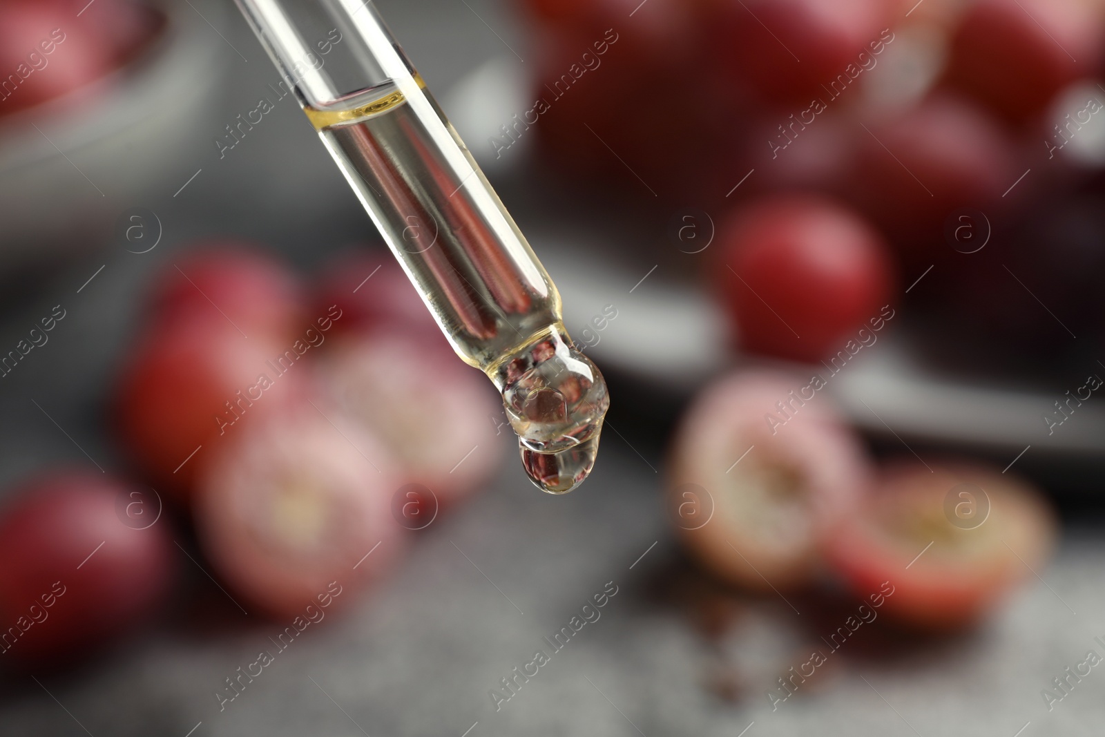 Photo of Dropper with natural grape seed oil on blurred background, closeup. Organic cosmetic