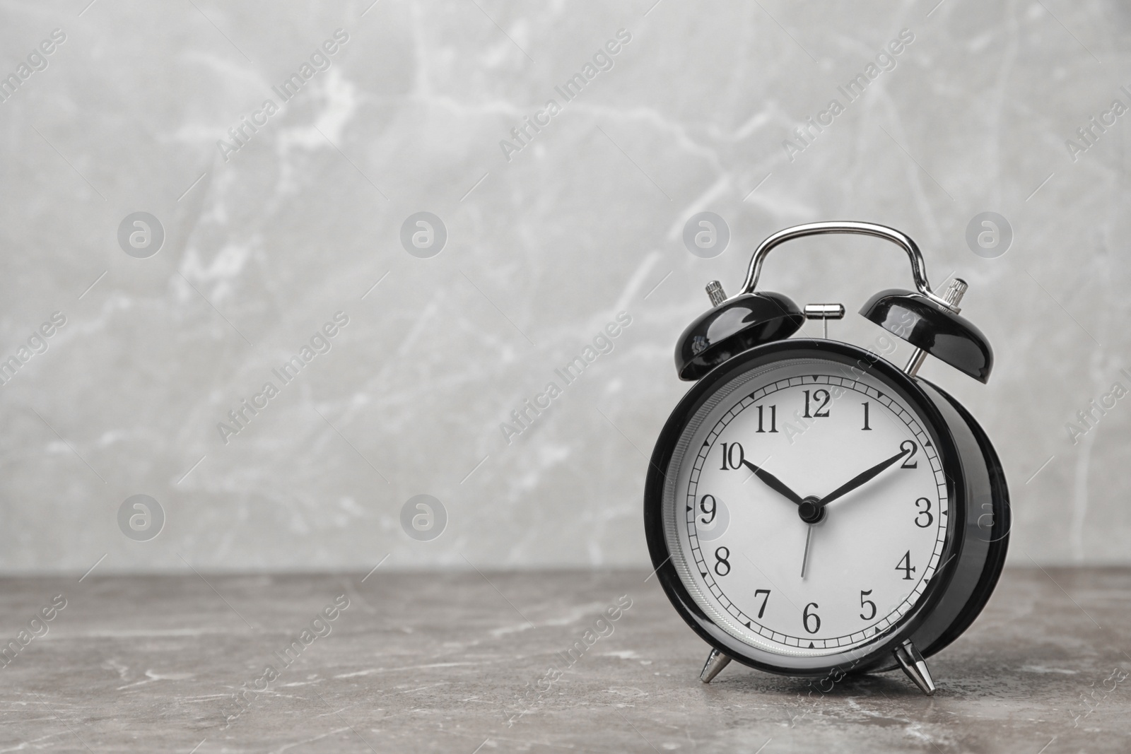 Photo of Alarm clock on table against grey background. Time concept