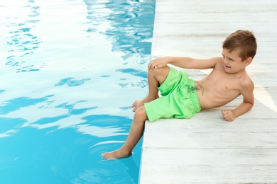 Photo of Little child near outdoor swimming pool. Dangerous situation