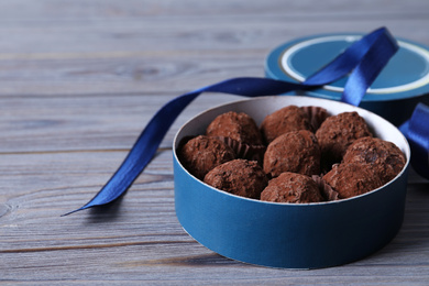 Photo of Box with tasty chocolate truffle candies on wooden table