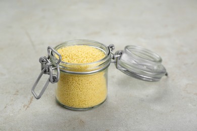 Photo of Glass jar of raw couscous on light table, closeup