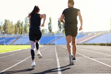 Sporty couple running at stadium on sunny morning