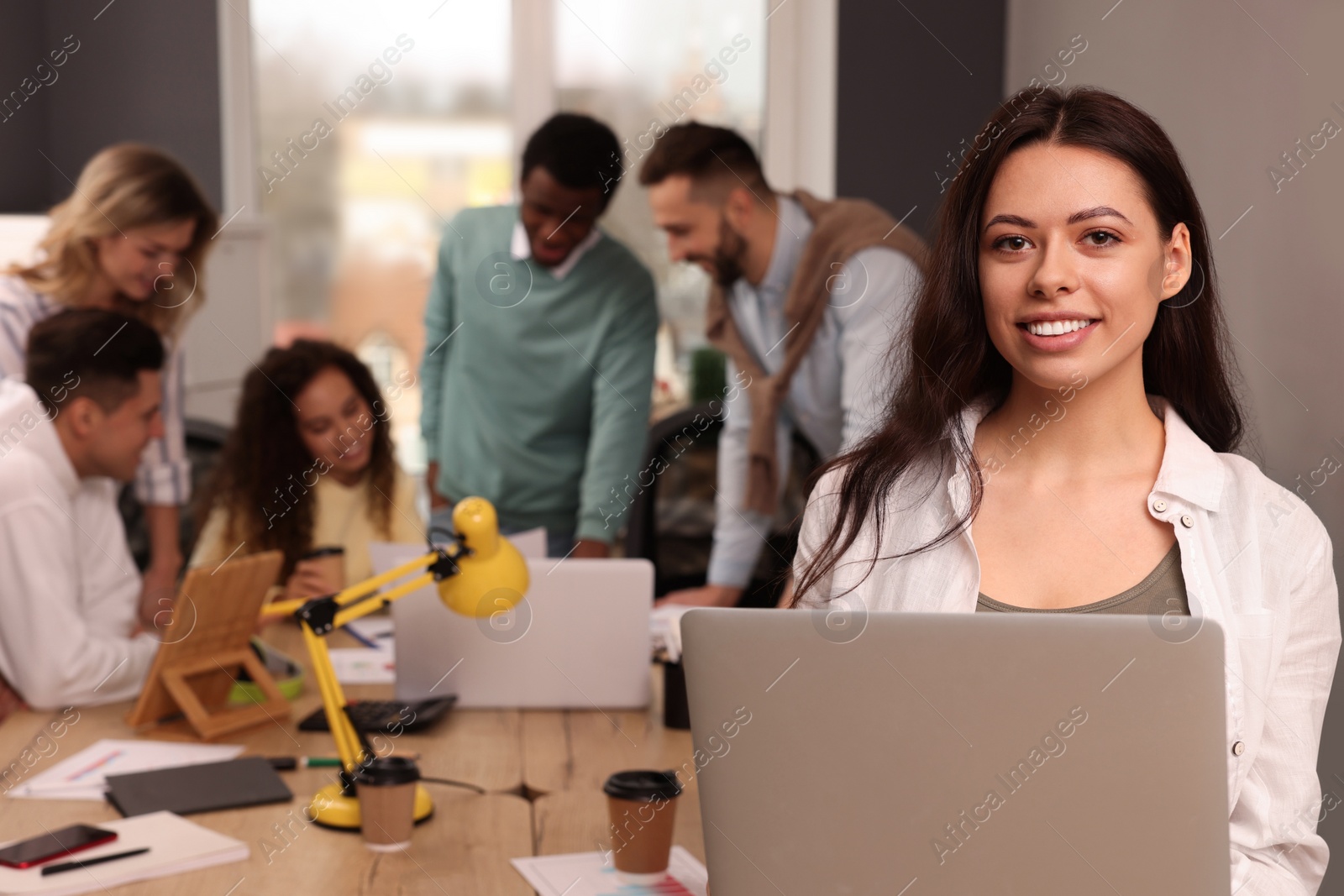 Photo of Portrait of happy young woman with laptop in office, space for text. Startup project