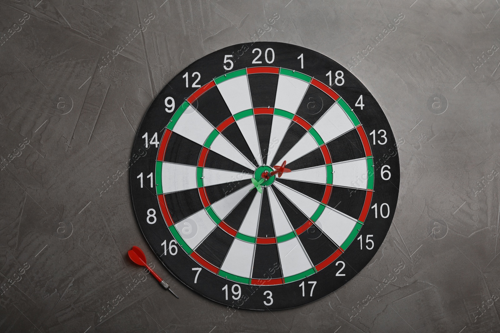 Photo of Dart board with color arrows on grey stone background, top view