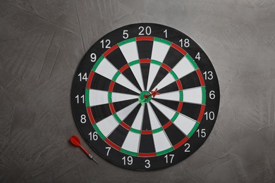 Dart board with color arrows on grey stone background, top view