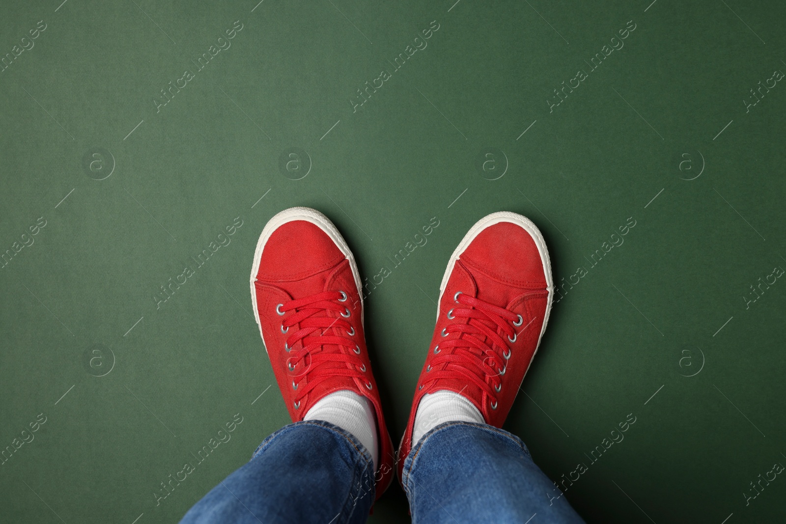 Photo of Woman in stylish sneakers on green background, top view