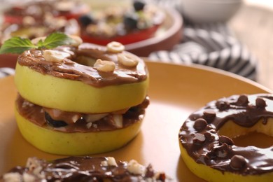 Photo of Fresh apples with nut butter, peanuts and chocolate chips on plate, closeup