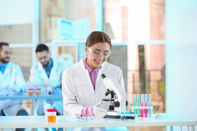 Young scientist working with microscope in laboratory. Chemical analysis