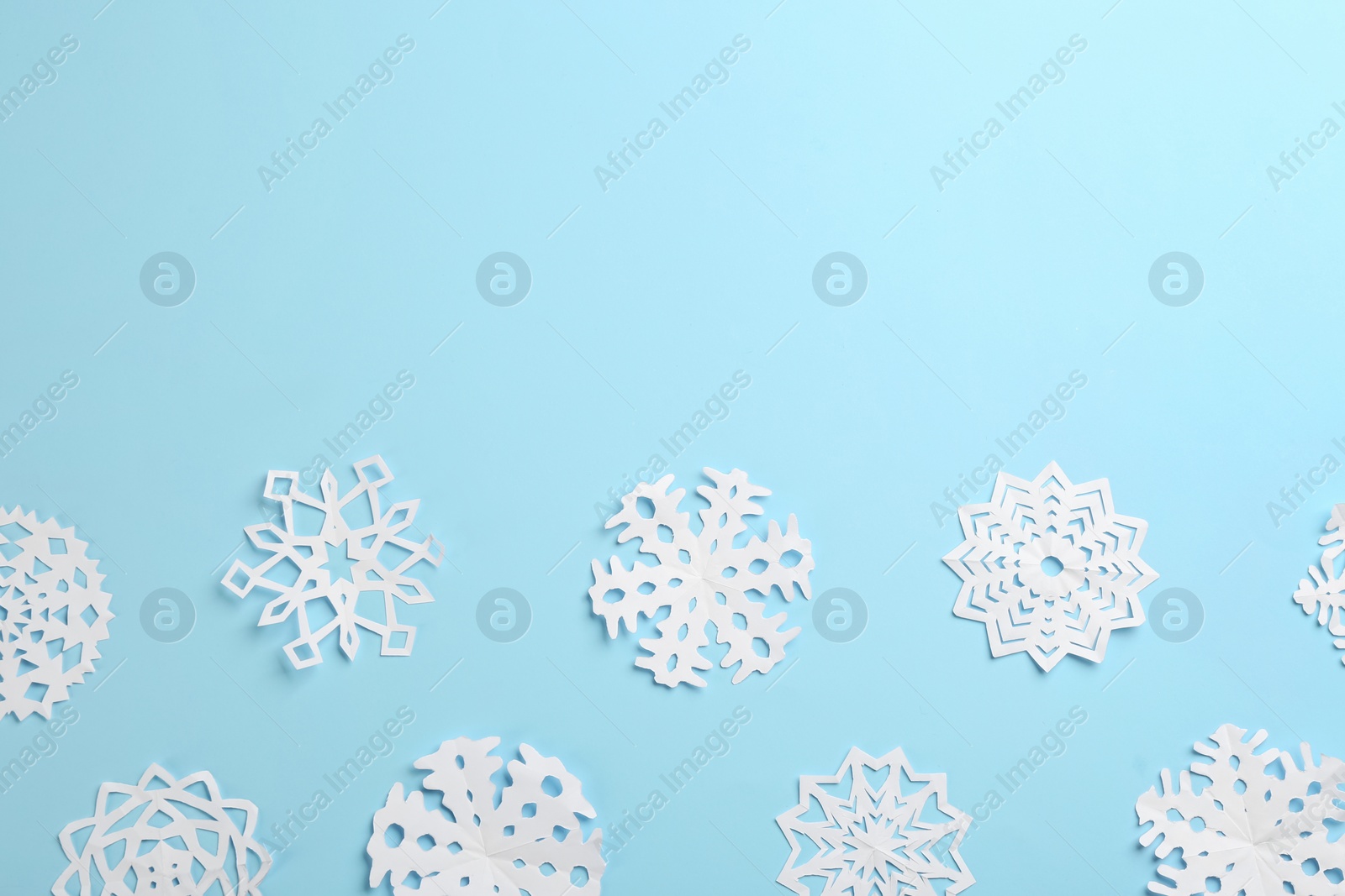 Photo of Many paper snowflakes on light blue background, flat lay. Space for text