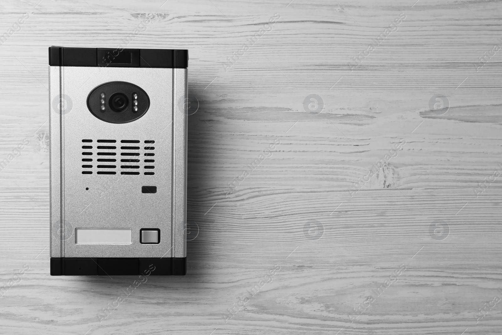 Photo of Modern intercom system with camera on white wooden background, top view. Space for text