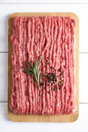 Photo of Raw ground meat, rosemary and peppercorns on white wooden table, top view