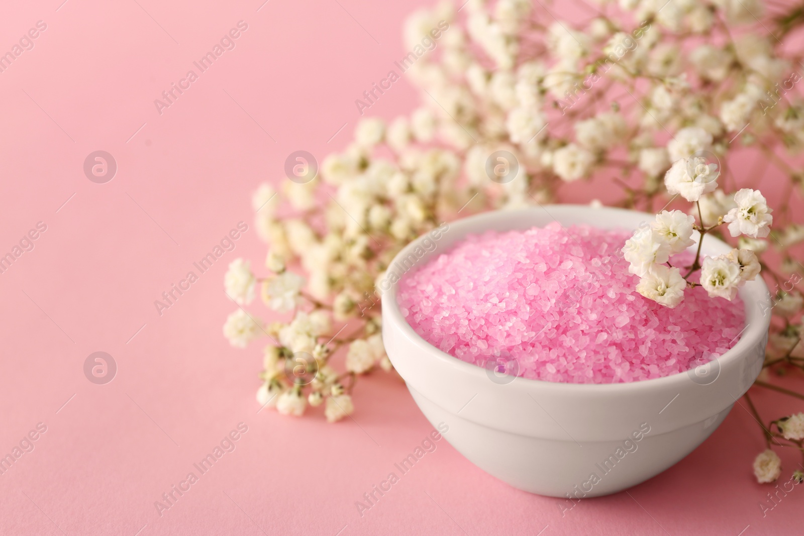 Photo of Aromatic sea salt and beautiful flowers on pink background, closeup. Space for text