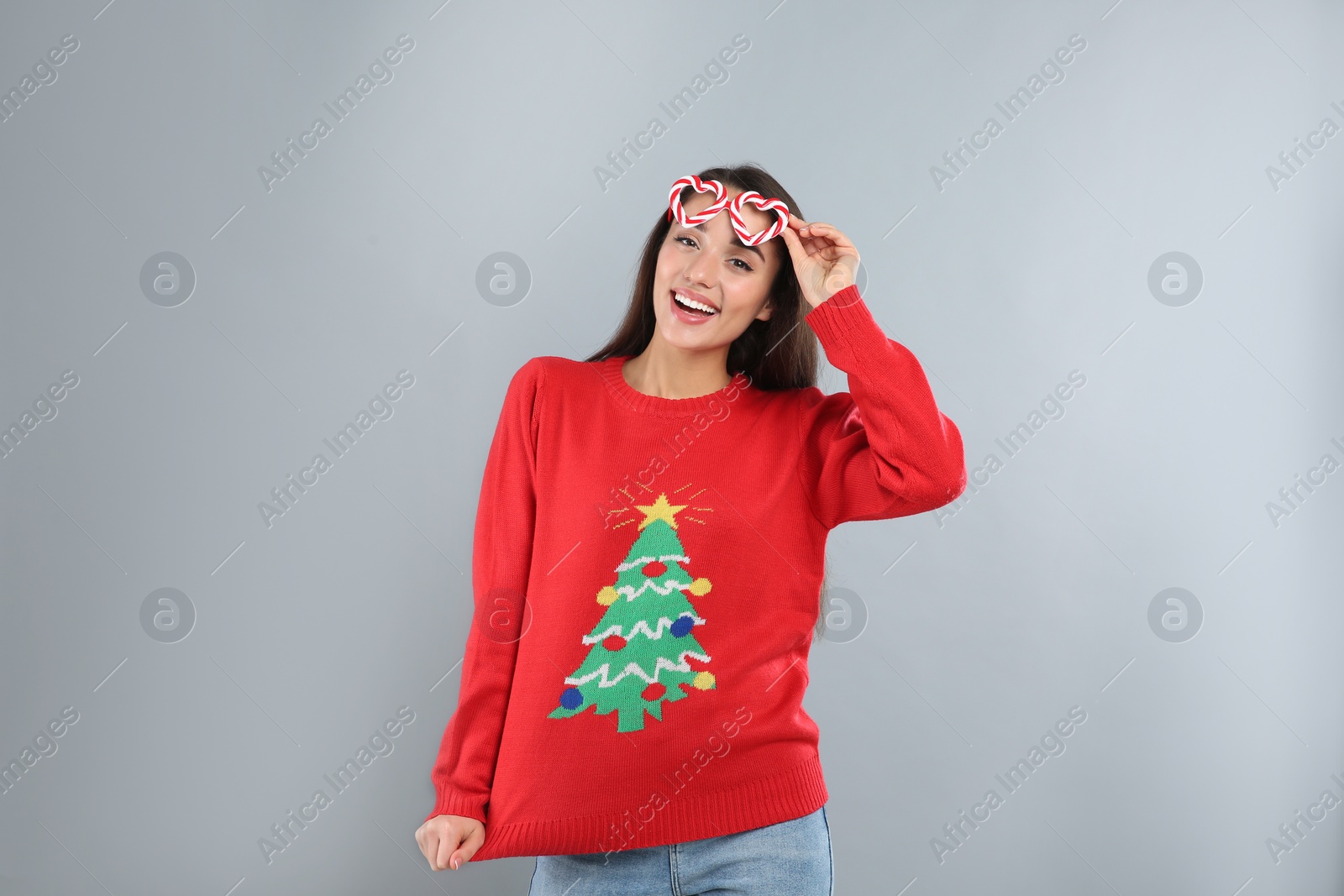 Photo of Young woman in Christmas sweater and party glasses on grey background