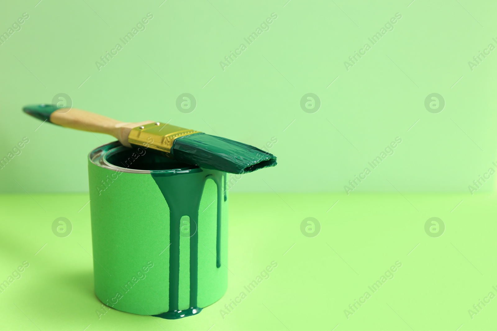 Photo of Can of green paint with brush on color background. Space for text