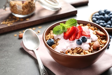 Photo of Delicious yogurt with granola and berries served on grey table