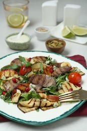 Photo of Delicious salad with beef tongue, grilled vegetables, peach, blue cheese and fork served on white table