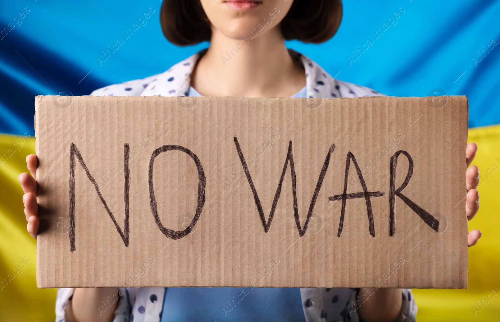 Photo of Woman holding poster with words No War near Ukrainian flag, closeup