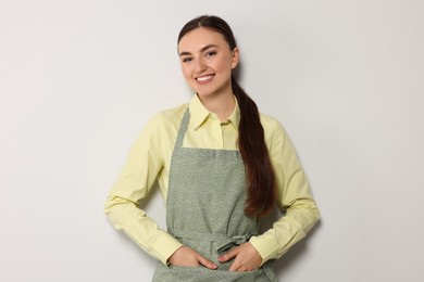 Photo of Beautiful young woman in clean apron with pattern on light grey background