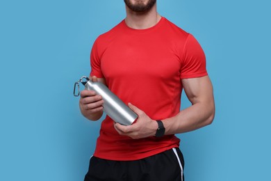 Photo of Sportsman with thermo bottle on light blue background, closeup