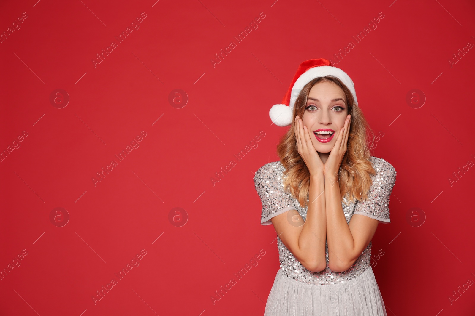 Photo of Emotional woman in Santa hat on red background, space for text. Christmas party