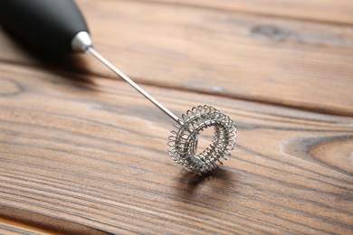 Photo of Black milk frother wand on wooden table, closeup