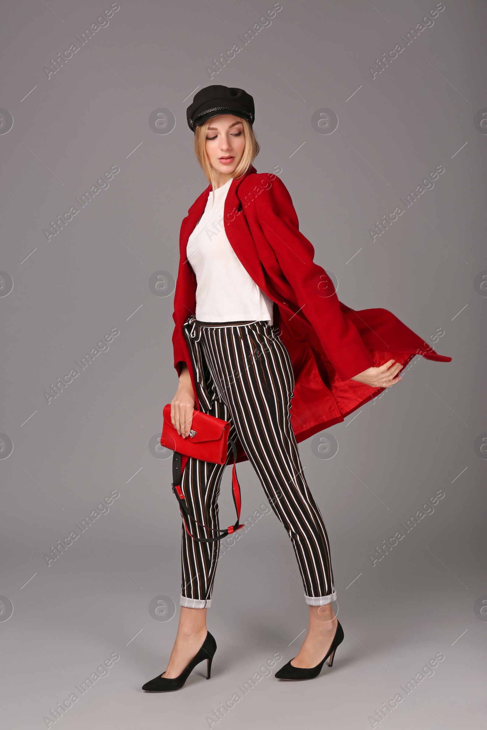 Photo of Young stylish woman in trendy shoes with bum bag on grey background