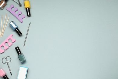 Photo of Nail polishes and set of pedicure tools on grey background, flat lay. Space for text