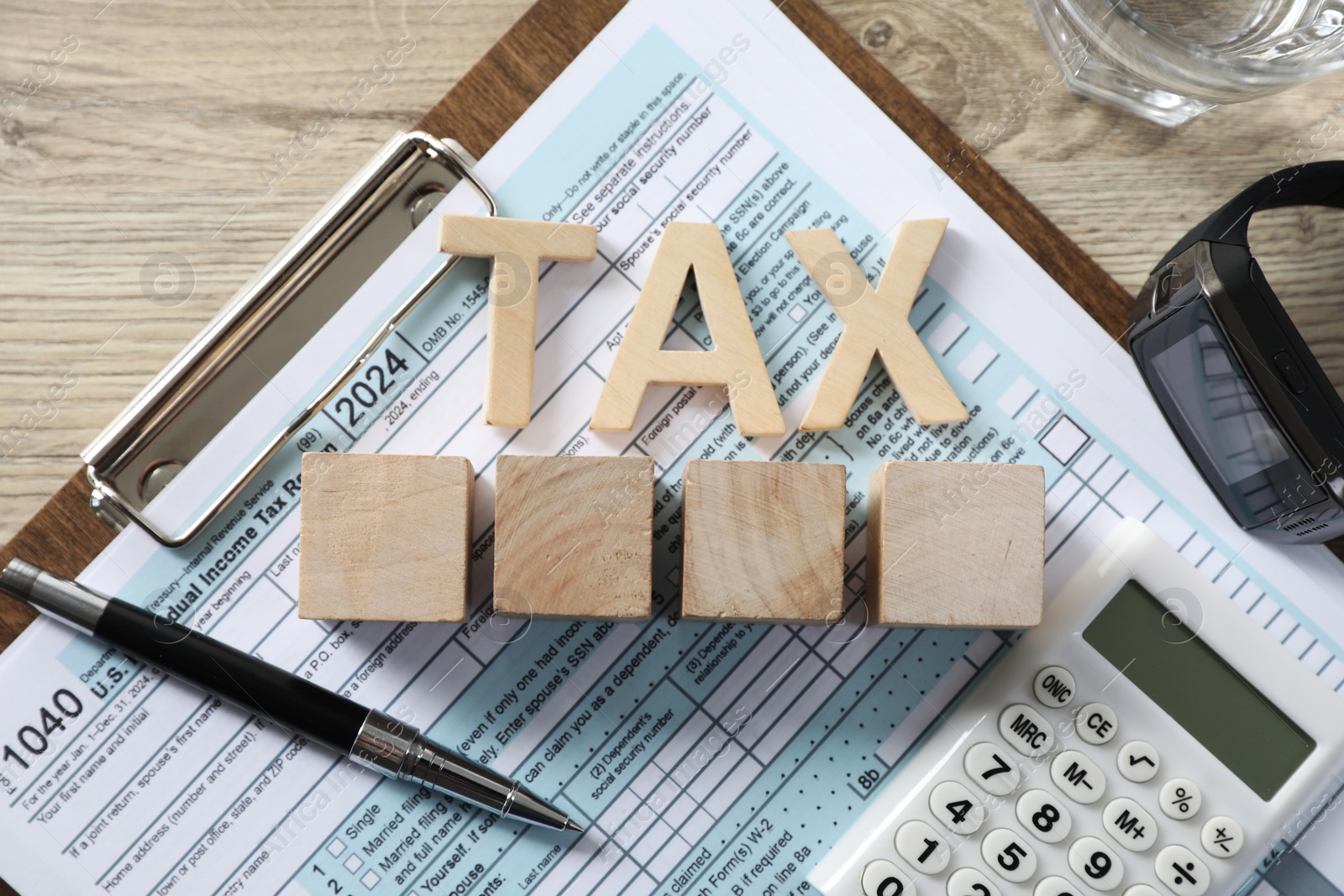 Photo of Word Tax, cubes, calculator, pen and document on wooden table, top view