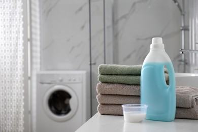 Photo of Stack of folded towels and detergents on white table in bathroom, space for text