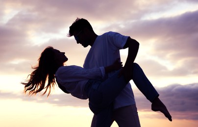 Image of Silhouette of lovely couple dancing on beach at sunset