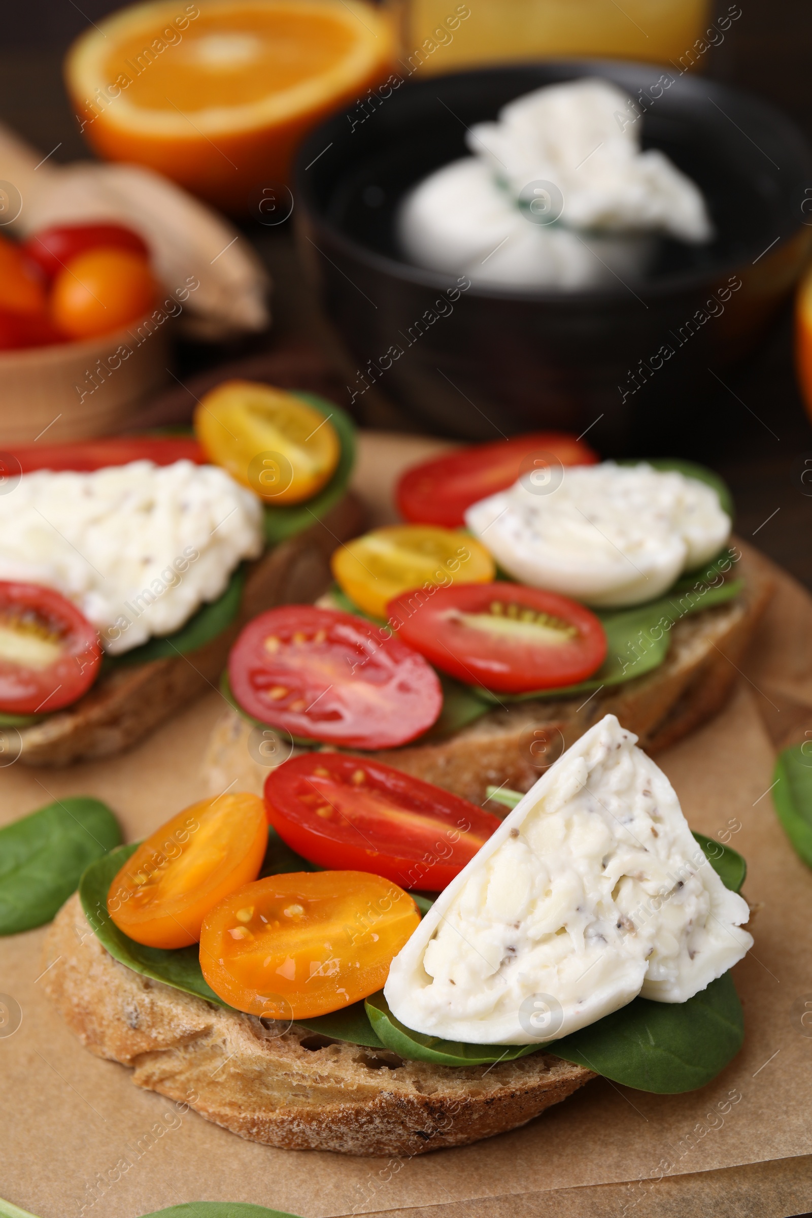 Photo of Delicious sandwiches with burrata cheese and tomatoes on table