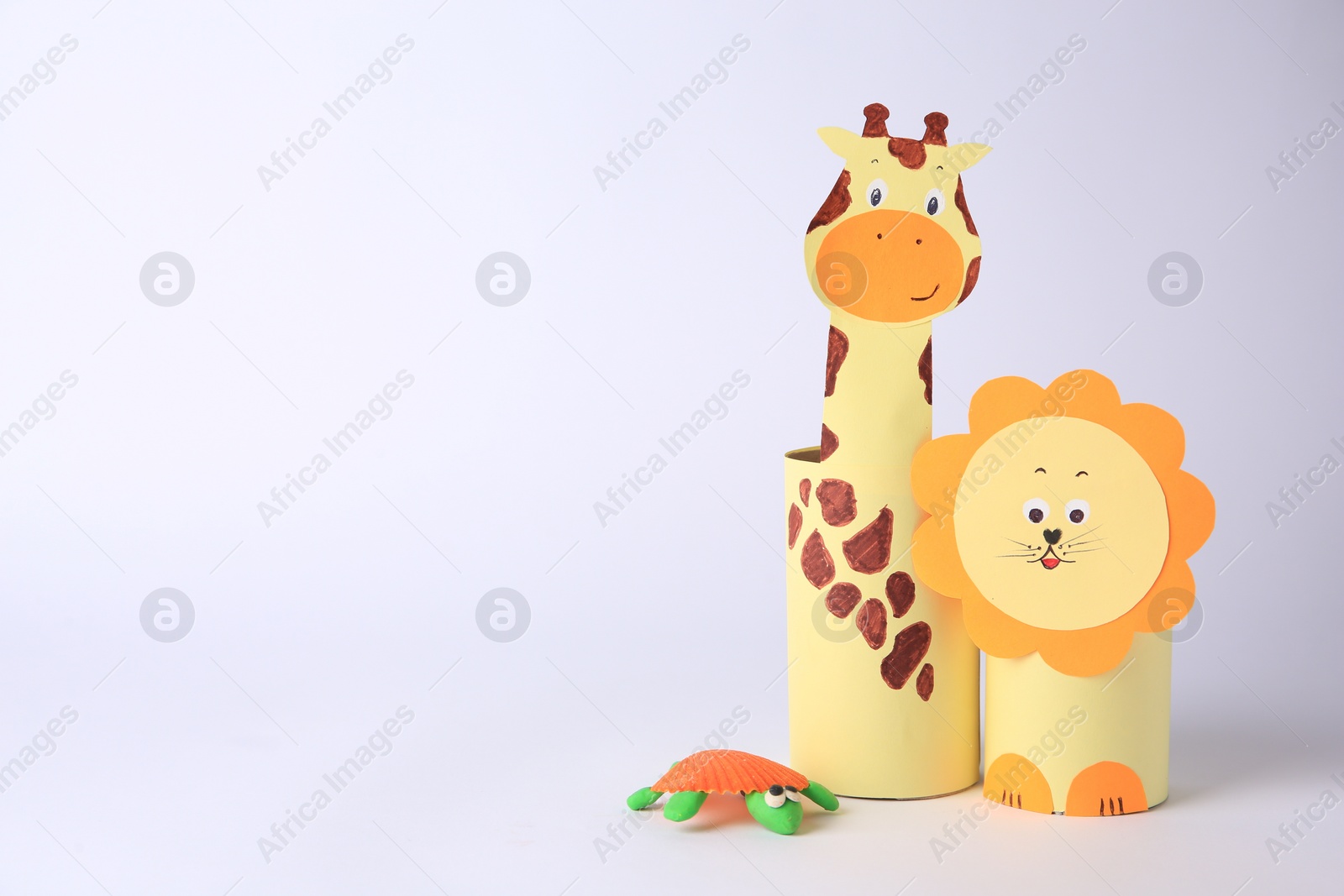 Photo of Toy giraffe and lion made from toilet paper hubs with plasticine turtle on white background, space for text. Children's handmade ideas