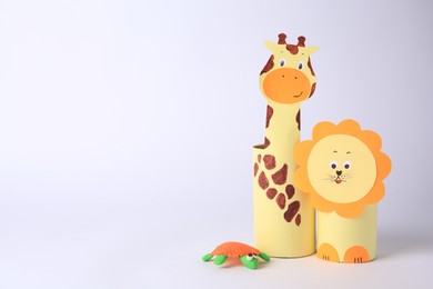 Photo of Toy giraffe and lion made from toilet paper hubs with plasticine turtle on white background, space for text. Children's handmade ideas