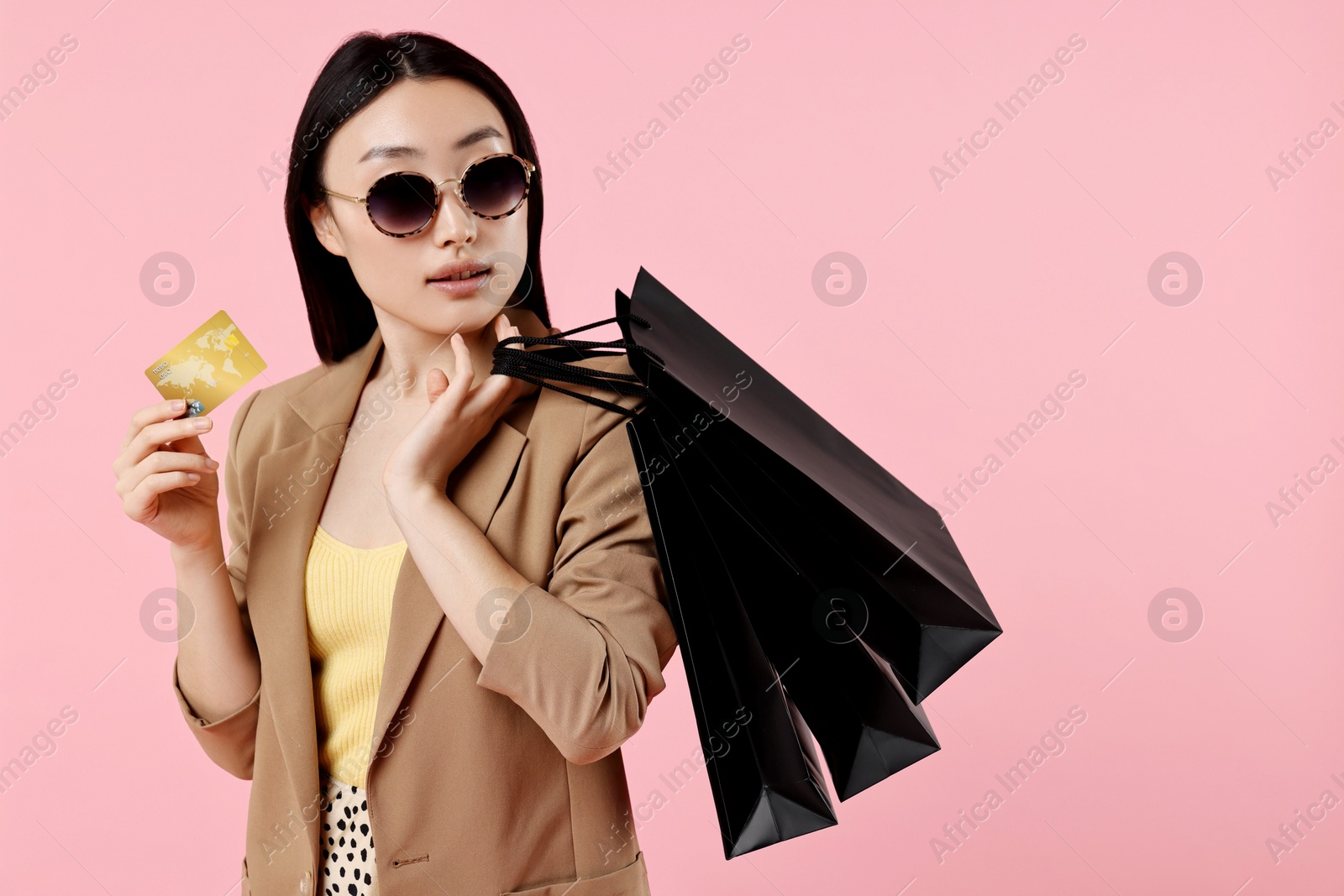 Photo of Beautiful woman with shopping bags and credit card on pink background. Space for text