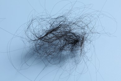 Photo of Pile of lost hair on light blue background